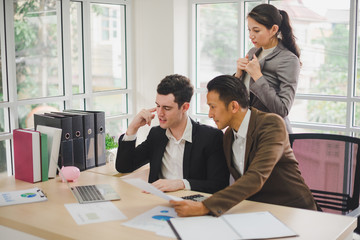 Businessmen are looking at the business plan and business results from the notebook in the office.