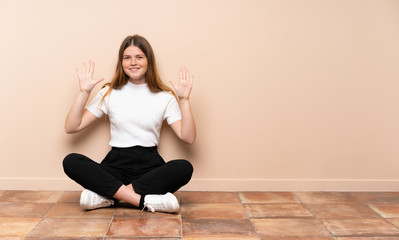 Ukrainian teenager girl sitting on the floor counting ten with fingers