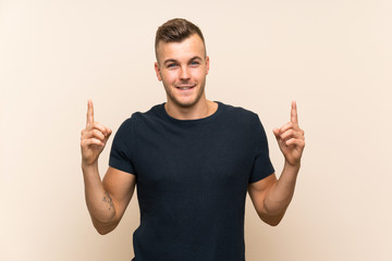 Young handsome blonde man over isolated background pointing up a great idea