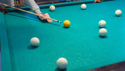 Green billiard table with white balls. Young man playing billiards
