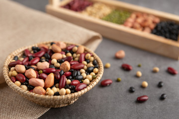 Grains or beans, red bean, black bean, green bean, soybean, peanut in the wooden tray and the wooden basket placed on the black cement floor. High angle view.