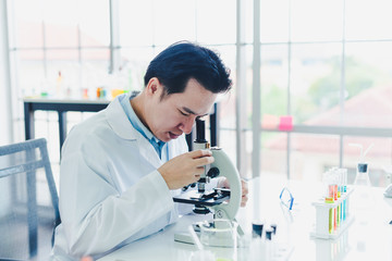 Asian scientists are preparing a microscope for laboratory testing and analysis. Science and...