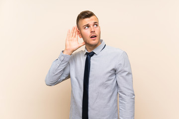 Young blonde businessman over isolated background listening something
