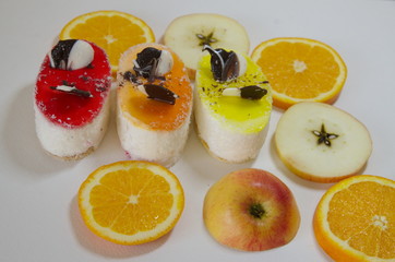 On a white background are delicious Exotica pastries sprinkled with coconut and chopped fruits: apples and oranges.