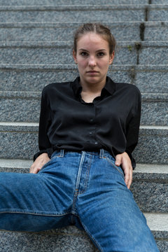 Young Woman Seated Leisurely on Outdoor Steps Looking at Camera