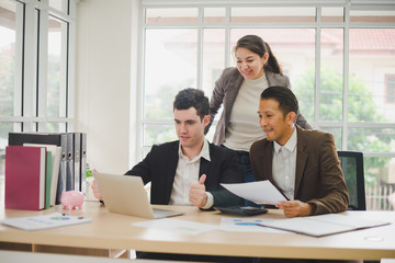 Businessmen are looking at the business plan and business results from the notebook in the office.