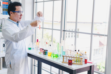 Asian scientists are preparing chemicals for testing and analysis in the laboratory. Scientists clear glasses and white shirts. Science and Chemistry Concept