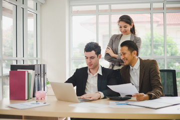 Businessmen are looking at the business plan and business results from the notebook in the office.