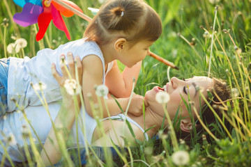 Portrait of happy mother and her little child on spring background. Cheerful family at dandelion...