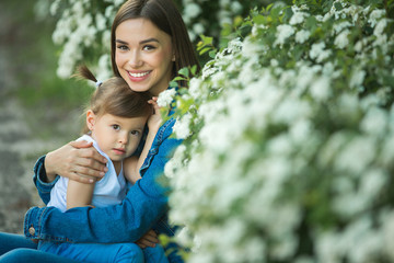 Cute family outdoors. Young pretty mother with her little daughter on floral background.