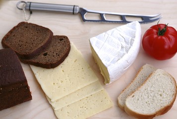 White and black bread, different varieties of cheese and knife view from above