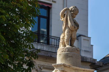 Fototapeta premium White statue of a small child on a background of house and blue sky
