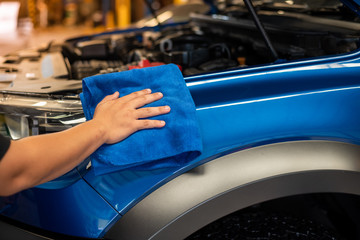 Hand with microfiber cloth cleaning car.