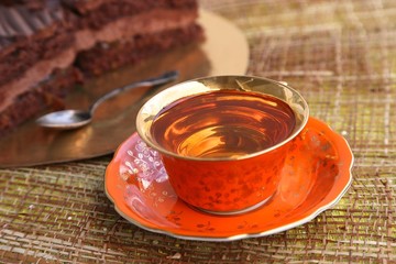 A piece of cake with chocolate filling and a cup of tea