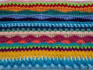 Multicolor wool crochet stitches blanket textile in bright colors background texture