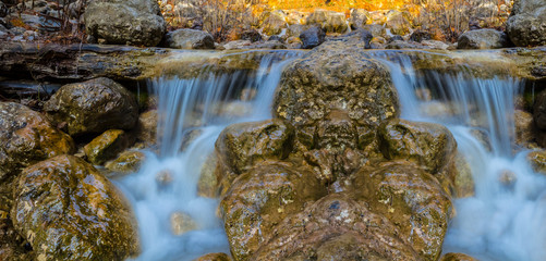 closeup small waterfall on a river rushing ower the stones