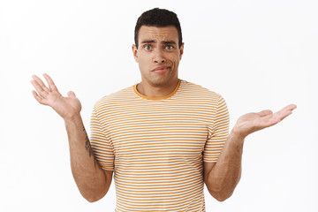 Clueless and confused young perplexed athletic man cant understand anything, shrugging spread hands...