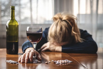 Woman taking pills and drinking alcohol. Drugs and alcohol abuse