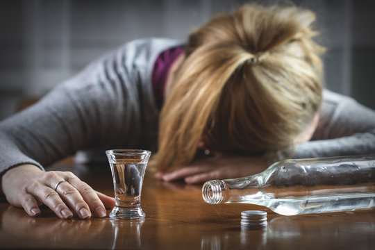 Drunk woman sleeping on table after drinking vodka. Alcohol abuse concept	