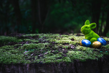 Easter bunny is sitting on a moss-covered tree trunk, find hidden easter eggs, concept, looking for...