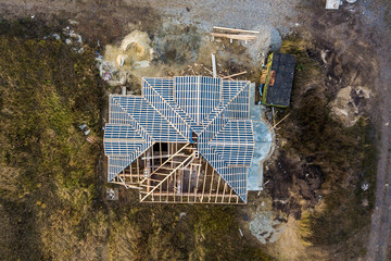 Private residential house with wooden roof frame structure under construction. Unfinished brick...