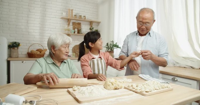 Senior Asian Couple Teaching Their Teen Granddaughter How To Prepare Dough For Dumplings, Spending Time Together - Childhood Memories, Family Ties Concept 4k Footage