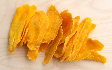 Mango fruit cut into long strips and dried in the sun, yellow lies on the board ready to eat for...