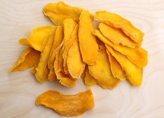 Mango fruit cut into long strips and dried in the sun, yellow lies on the board ready to eat for...