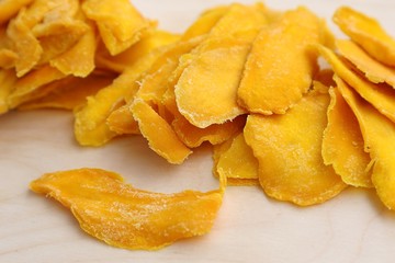 Mango fruit cut into long strips and dried in the sun, yellow lies on the board ready to eat for breakfast.