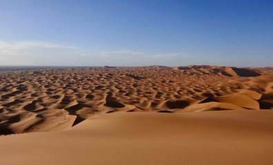 Sand dunes in Sahara with interesting shades and texture in desert landscape during sunset,...