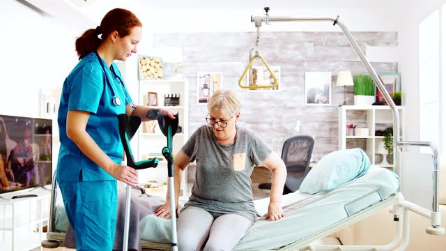 Social worker or nurse helping an elderly woman to walk with crutches