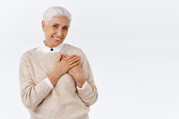 Lovely, touched senior wife receive charming gift for christmas or valentines day, press palms to heart feel flattered and delighted, smiling surprised with cute blush, stand happy white background