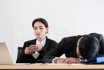 Two employees have lazy and playing the phone and sleep at the office in a relaxing time.