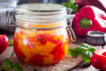 Fermented multicolored bell peppers in a glass jar, selective focus