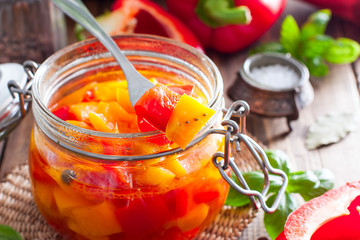 Fermented multicolored bell peppers in a glass jar, selective focus