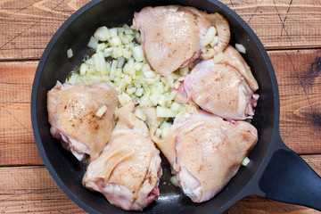 Step-by-step cooking of Spanish paella with chicken, shrimp and vegetables, step 3 - frying the chicken and adding onions and garlic, horizontal