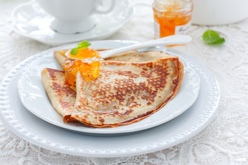 Breakfast with pancakes and orange jam, selective focus