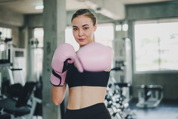 Fototapeta na wymiar Beautiful girls exercise by boxing in the gym. She wears a pink boxing glove and wears exercise.