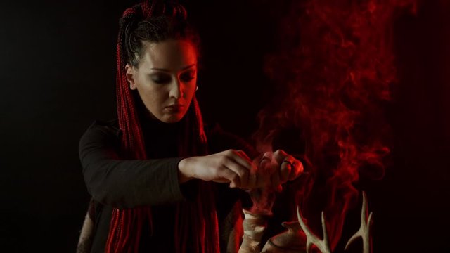Witch with braids adding ingredients to magic potion