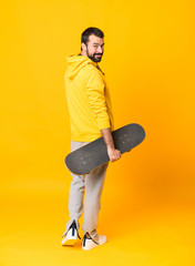 Full-length shot of a skater man over isolated yellow background