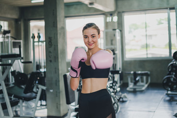 Fototapeta premium Beautiful girls exercise by boxing in the gym. She wears a pink boxing glove and wears exercise.