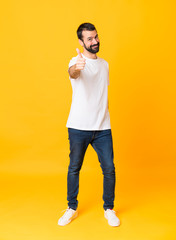 Full-length shot of man with beard over isolated yellow background with thumbs up because something...