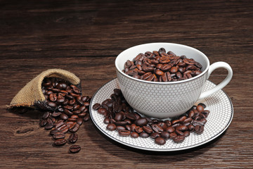 Coffee beans in the coffee cup and coffee beans on wood background
