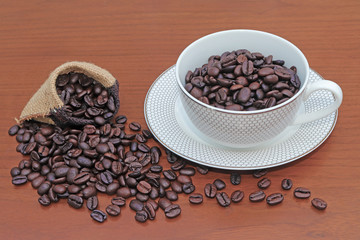 Coffee beans in the coffee cup and coffee beans on wood background