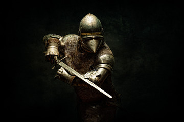 Portrait of a knight in armor, his sword in his hands, performing an attack parade - obrazy, fototapety, plakaty