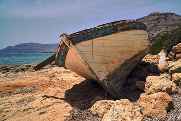 A dilapidated wooden boat on the seafront on the Greek island of Rhodes.