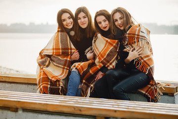 young and stylish four girls sitting on a bench in a winter park