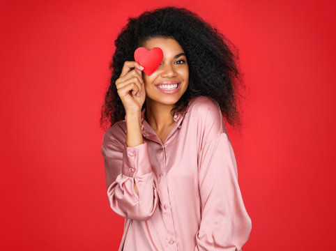 Happy girl holds red papers hearts and smiling. Photo of attractive latin girl in love on red background. Valentine's Day