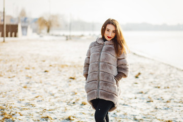young and stylish girl standing in a winter park