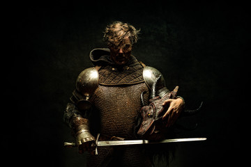 Portrait of a knight in armor, his sword in his hand, holding a dragon head in the other hand